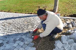 Pose de pavés Poseur de pavés sur une allée en granit gris